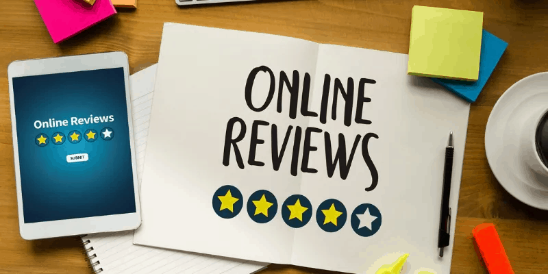 'Online reviews' written on a piece of paper with a cup of coffee and post-it notes on a table next to a phone with 'online reviews' and a star rating visible on the screen