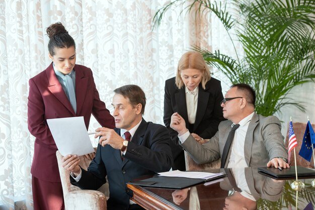 a group of people in suits looking at a piece of paper