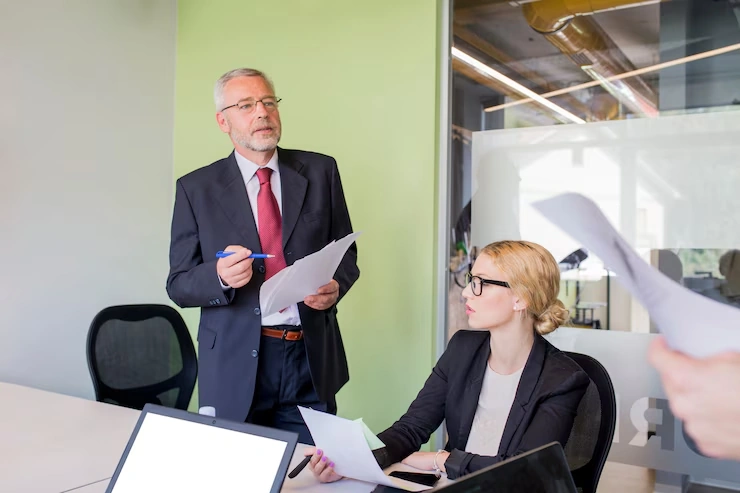 Senior executive reviewing reputation recovery documents with professional consultant in business meeting