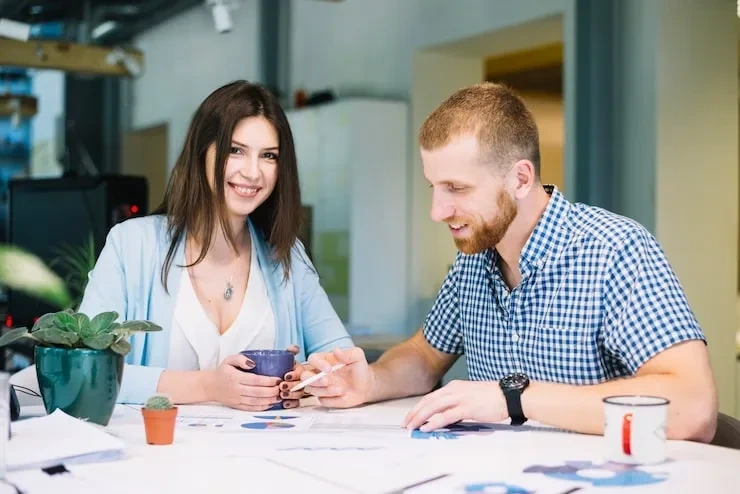 Woman and man smiling over PR documents at desk